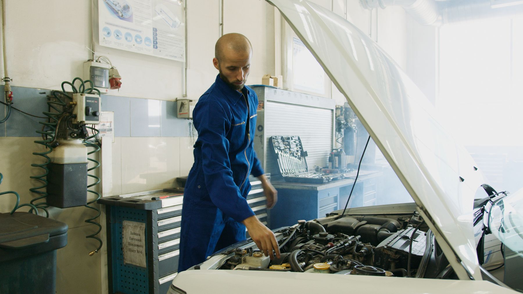 Mécanicien en bleu de travail qui contrôle un moteur